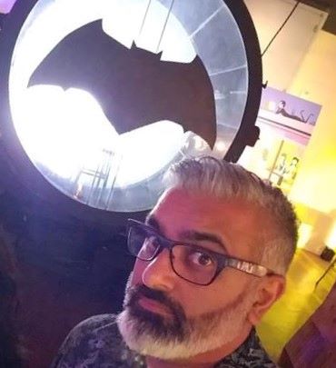 Portrait image of Minesh Lakhani with a bat signal in the background
