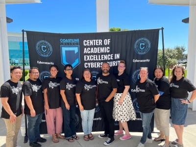 Group photo in front of the Coastline Center of Academic Excellence in Cybersecurity sign