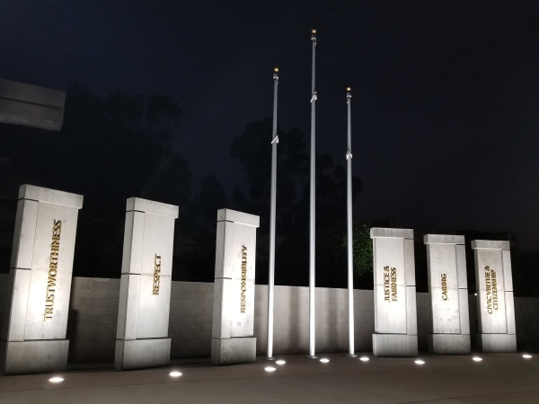 Flag poles in front of pillars with the words trustworthiness, respect, responsibility, justice and fairness, caring, and civic virtue and citizenship.